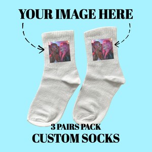 Puede incluir: Tres pares de calcetines blancos personalizados con una foto de dos personas en cada calcetín. El texto "3 PAIRS PACK CUSTOM SOCKS" está impreso debajo de los calcetines.