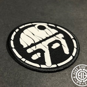 May include: Black and white embroidered patch with a circular design. The patch features a stylized graphic in white against a black background, with the text "DARK SIDE DOJO" in a circular border.