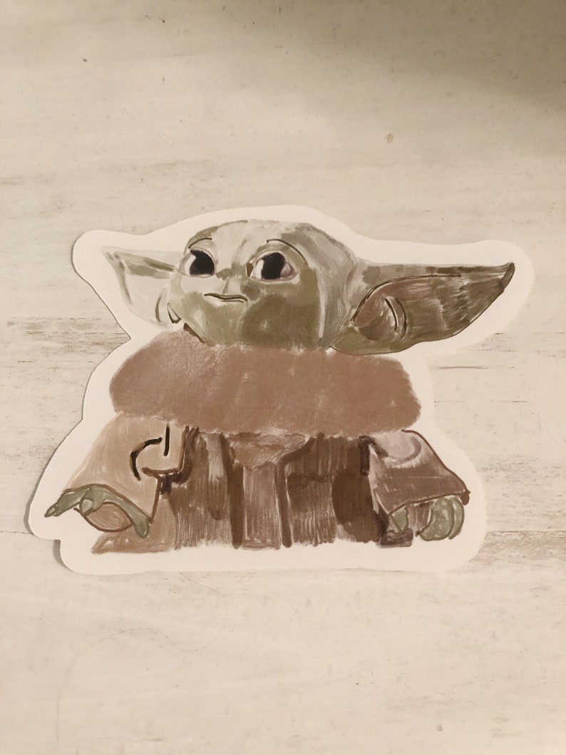 Op de afbeelding: Een sticker met een gestileerde illustratie van Grogu, ook bekend als Baby Yoda, uit The Mandalorian. Het kunstwerk toont Grogu in tinten groen, bruin en beige, met grote ogen en opvallende oren. De sticker heeft een witte rand.
