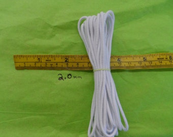 May include: A white elastic cord, approximately 2.0 mm in diameter, is coiled and measured against a ruler. The ruler is marked in inches and centimeters.