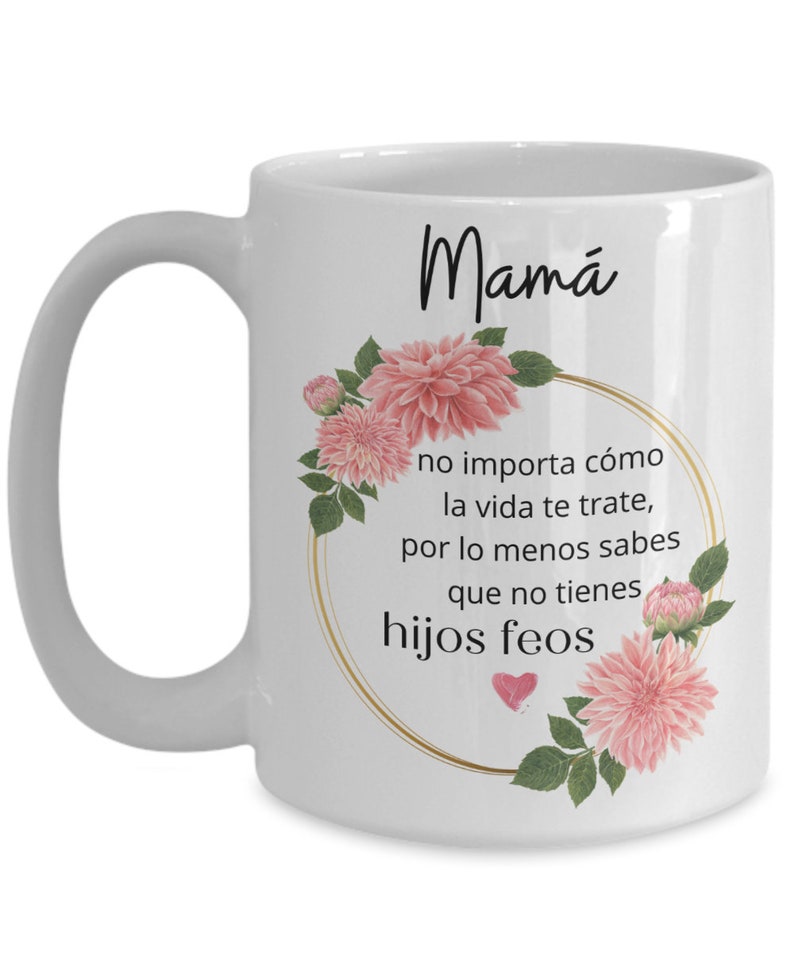 May include: White ceramic coffee mug with a black floral design and the text "Mam&aacute; no importa c&oacute;mo la vida te trate, por lo menos sabes que no tienes hijos feos".