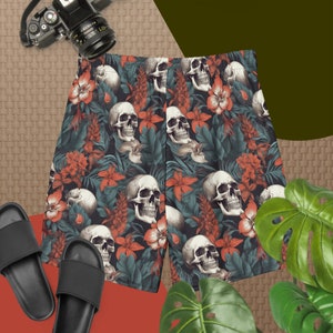 May include: Black and green swim trunks with a skull and tropical leaf pattern.