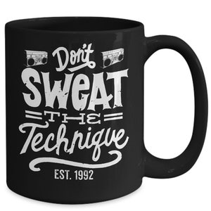 May include: Black ceramic coffee mug with white text that reads "Don't Sweat the Technique Est. 1992" and two images of cassette players.