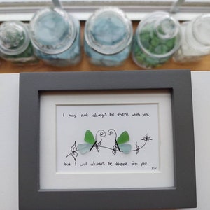 Puede incluir: Una pieza de arte enmarcada con una imagen dibujada a mano de dos mariposas hechas de vidrio de mar. El texto dice "Puede que no siempre esté ahí contigo, pero siempre estaré ahí para ti."