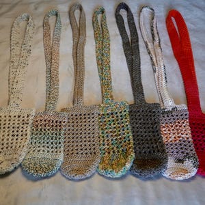 May include: Seven crocheted bags with different colored yarn. The bags have a long strap and are made with a simple crochet stitch.