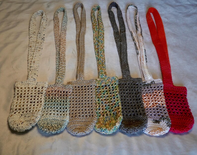May include: Seven crocheted bags with different colored yarn. The bags have a long strap and are made with a simple crochet stitch.