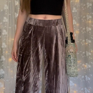 May include: A pair of wide-leg pants made of a soft, crushed velvet fabric. The pants are a light brown color and have a high waist. The fabric has a subtle sheen and a slightly textured surface.