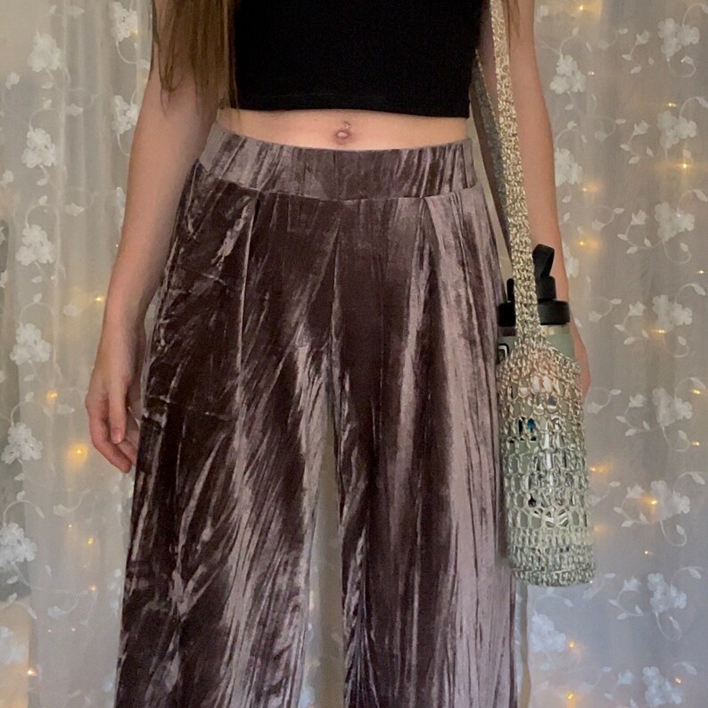 May include: A pair of wide-leg pants made of a soft, crushed velvet fabric. The pants are a light brown color and have a high waist. The fabric has a subtle sheen and a slightly textured surface.