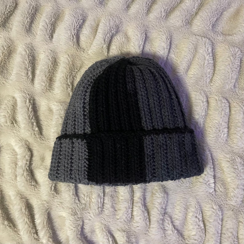 May include: A gray and black knitted beanie hat with a checkered pattern.