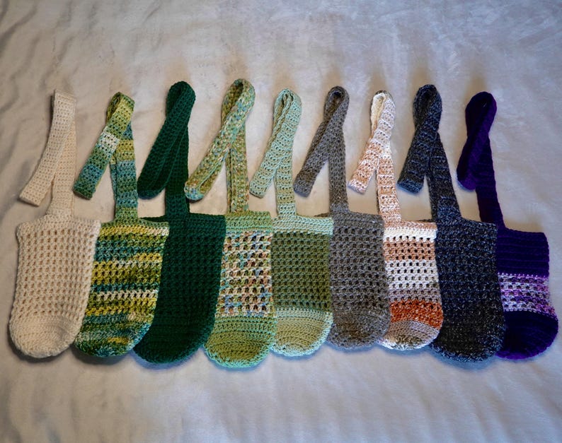 May include: Ten crocheted bags with different colored stripes and patterns. The bags have long straps and are made of a soft, textured yarn.