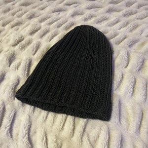 May include: A black knitted beanie hat with a ribbed texture.