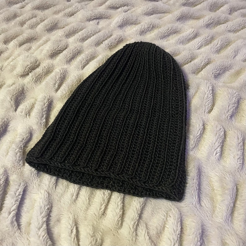 May include: A black knitted beanie hat with a ribbed texture.