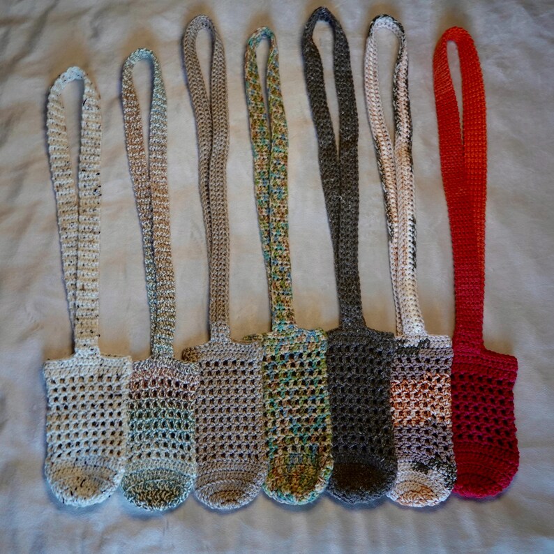 May include: Seven crocheted bottle holders in various colors, including white, beige, green, gray, and red. The holders are made with a simple, open stitch pattern and have long straps for carrying.