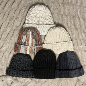May include: Six knitted winter hats in a variety of colors and styles. The hats are arranged in a pyramid shape, with the largest hat at the top and the smallest hats at the bottom.