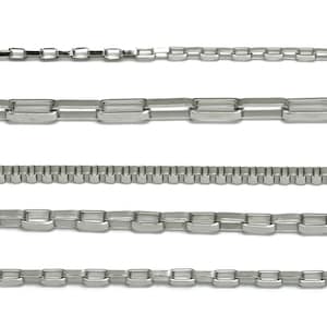 Puede incluir: Una colección de cadenas de metal plateado en varios diseños. Las cadenas se muestran horizontalmente sobre un fondo blanco. Los diseños incluyen estilos de eslabones de caja, curb y otros, mostrando diferentes anchos y patrones.