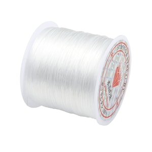 May include: A spool of white elastic string for jewelry making. The spool has a label that says "Strong & Stretchable" in red text.