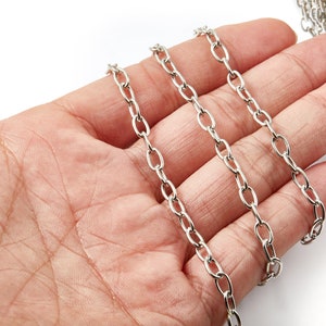 May include: Silver chain links in a variety of lengths, displayed on a hand.