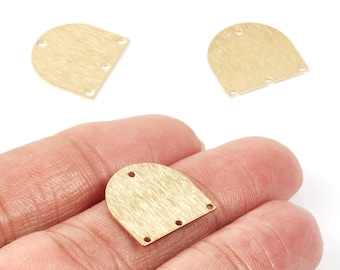 May include: Close-up of several brass-coloured metal jewellery components. The components are in a half-circle shape with three holes at the bottom and two at the top. One component is held in a hand.