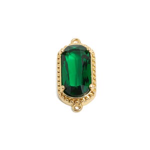 May include: A gold-toned pendant with a green emerald-shaped glass stone in a decorative frame. The pendant has two loops on the top for attaching to a chain.
