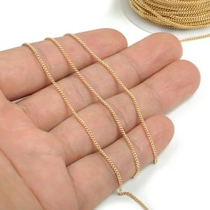 May include: Gold chain with a delicate, twisted design. The chain is shown in a hand, with multiple strands laid out for display.