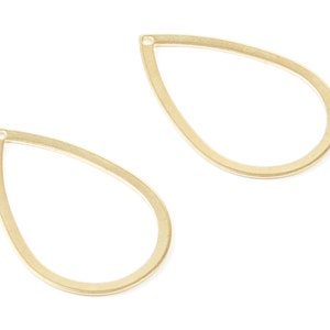 Puede incluir: Dos piezas en blanco para pendientes en forma de lágrima de metal dorado con un pequeño agujero en la parte superior.