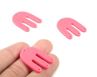 May include: Three pink, abstract-shaped charms with a rounded top and three prongs. Each charm has a small hole at the top and at the end of each prong. One charm is held in a hand.