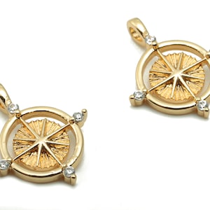 Puede incluir: Dos colgantes de tono dorado con un diseño de estrella y brillantes transparentes. Los colgantes son redondos y tienen un diseño de estrella en relieve en el centro. Los brillantes están engastados alrededor del borde de los colgantes.