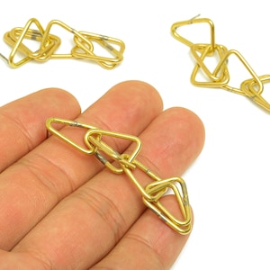 May include: Gold-toned metal earrings with a geometric design. The earrings feature interconnected triangular shapes, creating a chain-like appearance. The design is simple and modern, suitable for everyday wear.