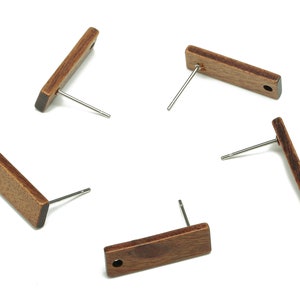 May include: Five pairs of wooden earrings with silver posts. The earrings are rectangular in shape and have a dark brown wood grain.