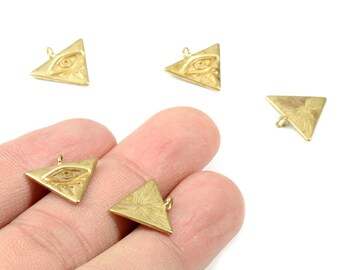 Peut inclure: Charm triangulaire doré avec un motif d'œil. Les breloques sont petites, avec une boucle en haut pour les attacher à des bijoux. L'œil est détaillé et les triangles ont une surface texturée.