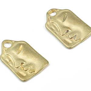 Puede incluir: Dos abalorios de metal dorado en forma de cara. Cada abalorio tiene un agujero en la parte superior para sujetarlo a un collar o pulsera.