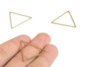 Puede incluir: Tres colgantes triangulares dorados de marco abierto. Uno se sostiene en una mano, mientras que otros dos están dispersos sobre una superficie blanca. Estas formas geométricas son ideales para la fabricación de joyas o proyectos de artesanía.