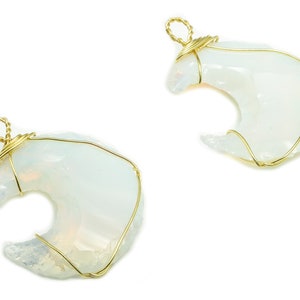 Può includere: Due ciondoli a forma di mezzaluna in opale bianco avvolti in filo d'oro. I ciondoli misurano circa 5 cm di lunghezza e 2,5 cm di larghezza.