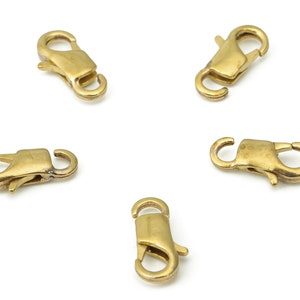 Puede incluir: Cinco cierres de langosta de metal dorado, un tipo de cierre utilizado para la fabricación de joyas.