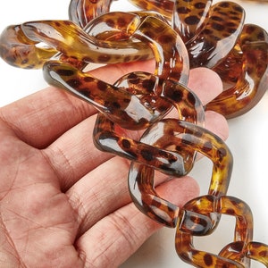 Könnte beinhalten: Eine braune und schwarze Plastikkette mit einem Schildpattmuster. Die Kette besteht aus großen, klobigen Gliedern.