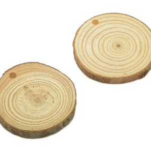 Puede incluir: Dos rodajas de madera redondas con un agujero perforado en el centro. Las rodajas son de color marrón claro con vetas de madera visibles.