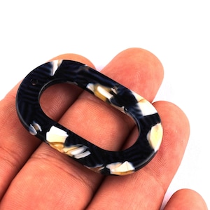 Peut inclure: Perle ovale en acrylique avec un motif marbré noir, blanc et beige. La perle a une finition polie et un trou pour l'enfilage. Convient à la fabrication de bijoux et à d'autres projets d'artisanat.