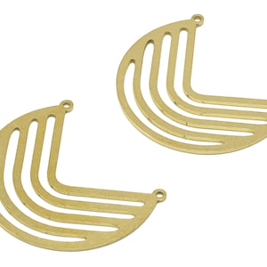 May include: Two gold metal half-circle shapes with a geometric design. Each shape has five curved lines that create a pattern.