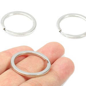 May include: Silver-colored key rings, perfect for organizing keys or attaching charms. The rings are round with a split for easy attachment. One ring is held in a hand, while two others are displayed separately against a white background.