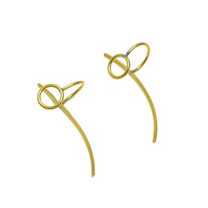 Può includere: Un paio di orecchini dorati con un semplice design a cerchio. Ogni orecchino presenta un filo curvo che forma un cerchio nella parte superiore e poi si estende verso il basso in una forma curva.