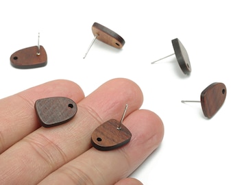 May include: Five wooden earrings with a dark brown color and a natural wood grain pattern. The earrings are shaped like a teardrop with a small hole at the top for the post. The earrings are displayed on a hand and on a white surface.