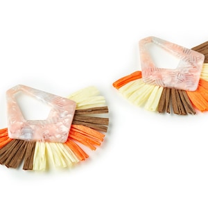 May include: A pair of earrings with a geometric, pink and white, translucent, resin-like design. Each earring has a fringe of brown, yellow, and orange fabric.
