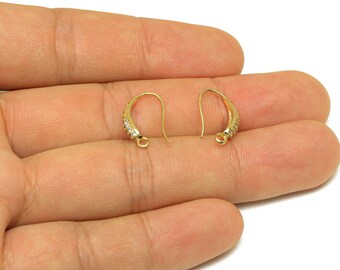 May include: Two gold-colored earring hooks with a curved design. The hooks have a small loop at the bottom and are partially encrusted with small, clear gemstones. The earrings are displayed on a light-colored background.