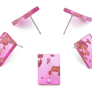 May include: A pair of pink rectangular stud earrings with gold flakes embedded in the resin. The earrings have silver posts.