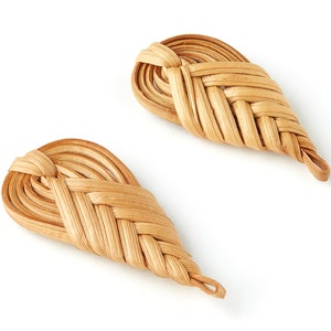 Puede incluir: Dos adornos tejidos, de color marrón claro, en forma de lágrima, hechos de materiales naturales.