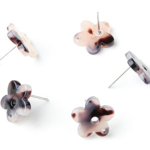 May include: Four pairs of flower-shaped earrings with a white and brown marbled pattern. The earrings have a silver post.