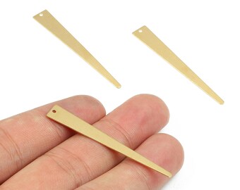 Könnte beinhalten: Drei goldfarbene, längliche, dreieckige Metallanhänger. Jeder Anhänger hat oben ein kleines Loch zum Auffädeln. Ein Anhänger wird in einer Hand gehalten, während die anderen beiden darüber positioniert sind.