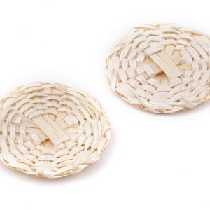 Puede incluir: Dos posavasos redondos, tejidos, de color marrón claro con un patrón tejido. Los posavasos están hechos de materiales naturales y tienen un aspecto rústico.