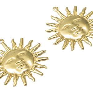 May include: Two gold-toned metal sun charms with a face on each. The sun has a raised face and rays around the edge.