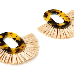 Peut inclure: Une paire de boucles d'oreilles ovales brunes et noires avec une frange de raphia beige.